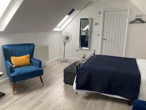 a bedroom with a bed and a blue chair at Loft apartment in Herstmonceux