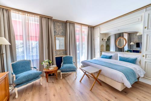 a bedroom with a bed and two blue chairs at Carlton Lausanne Boutique Hôtel in Lausanne