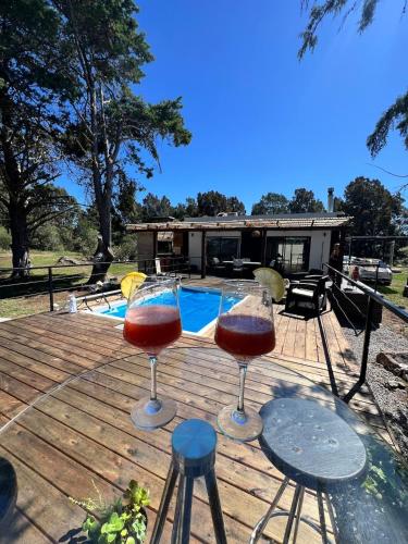two glasses of wine sitting on a deck with a pool at NuestroSueño in Villa Serrana