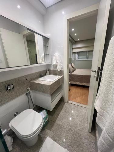 a bathroom with a toilet and a sink and a bed at LRFlat - Ambiente climatizado, moderno, confortável e próximo a tudo! in Montes Claros