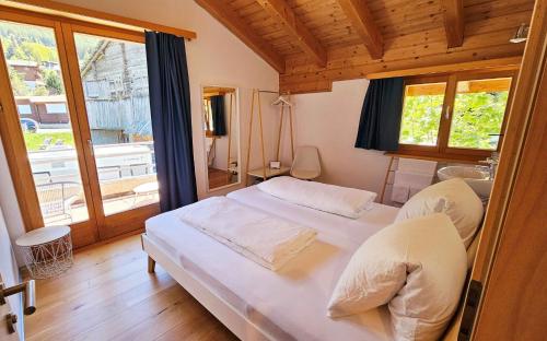 a bedroom with a white bed and a window at Gästehaus auf Camping Grächbiel in Grächen