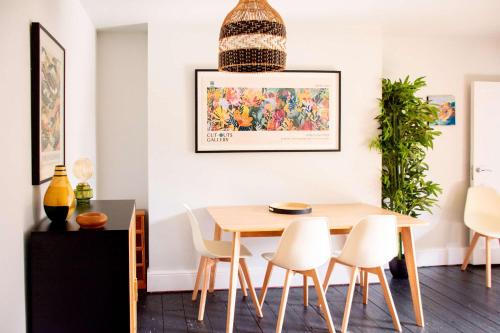 a dining room with a wooden table and white chairs at Rosa's Retreat - By Rowes Retreats in Falmouth