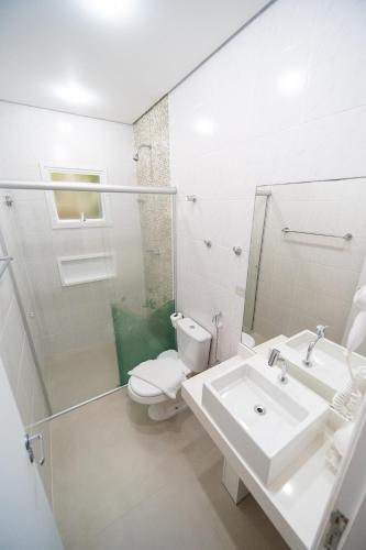 a white bathroom with a toilet and a sink at Pousada Etoile in Juquei