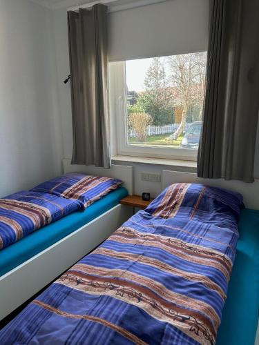 two beds in a room with a window at Haus-am-Deich in Wittdün