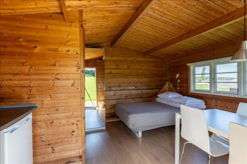 a bedroom in a log cabin with a bed and a table at Vikær Strand Camping & Cottages in Diernæs