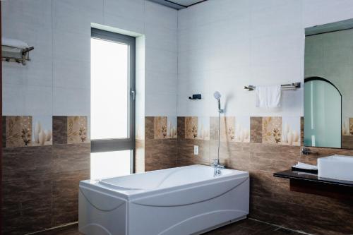 a bathroom with a large tub and a mirror at BEN Villa in Cẩm Phả Mines