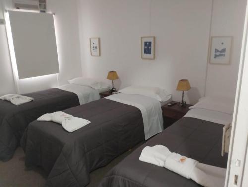 a hotel room with three beds with towels on them at La Posada de los Robles in Las Grutas
