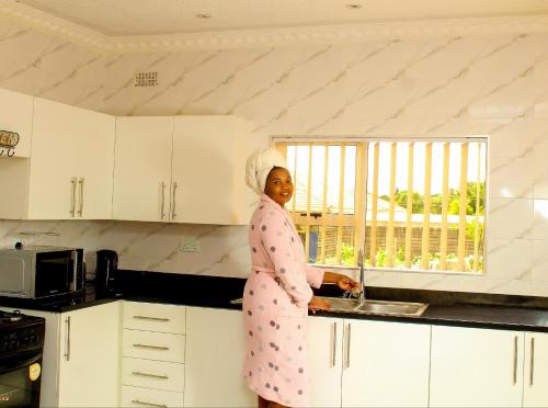 a woman standing in a kitchen with a sink at Lion Haven Guest House in Harare