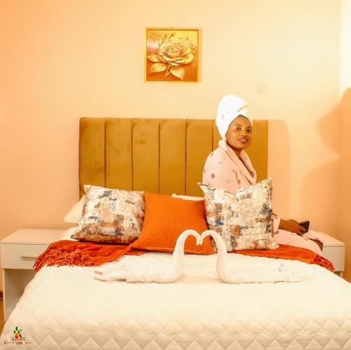 a woman sitting on a bed with a swan on it at Lion Haven Guest House in Harare