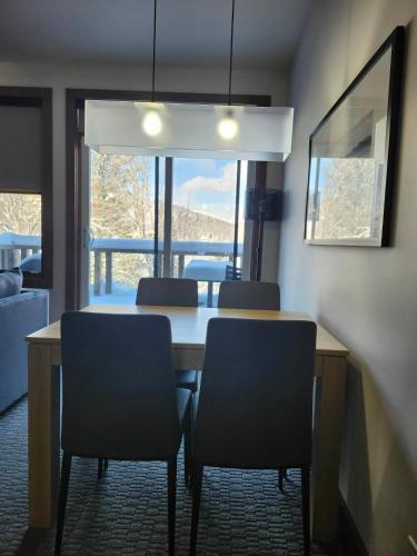 a dining room with a table and chairs and a window at 3306 Studio, Condo sur le Lac in Lac-Superieur
