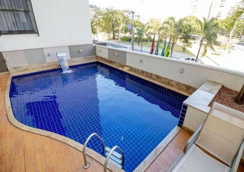 a large swimming pool with blue water in a building at Sun Square Suítes By Temporada Gyn in Goiânia