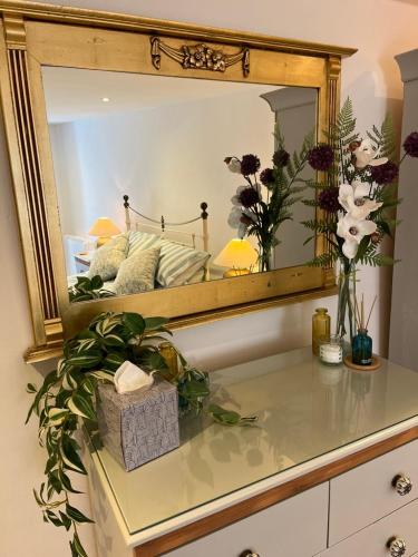 a mirror sitting on top of a dresser with flowers at Ship Cottage Tenby Beach 50m in Pembrokeshire