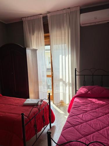a bedroom with two beds with red sheets and a window at Antico Borgo in Tarsia