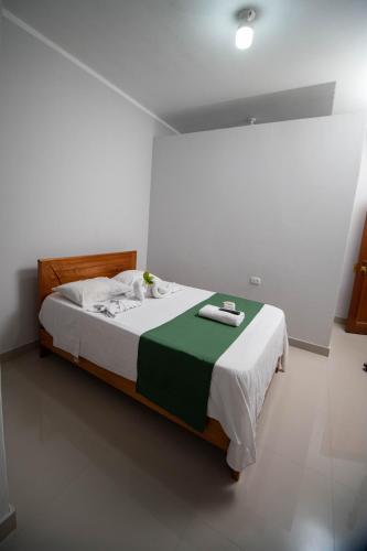a bedroom with a bed with a green and white blanket at Hospedaje Humazapa in Tarapoto
