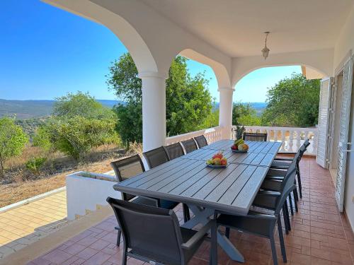 a porch with a wooden table and chairs on it at BnB Homes Luxurious Villa Stardust with Swimming pool & BBQ for Family Fun in Ameijoafas