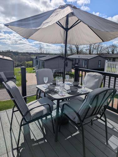 a table and chairs with an umbrella on a deck at Holiday Home with a Hot tub in St Austell