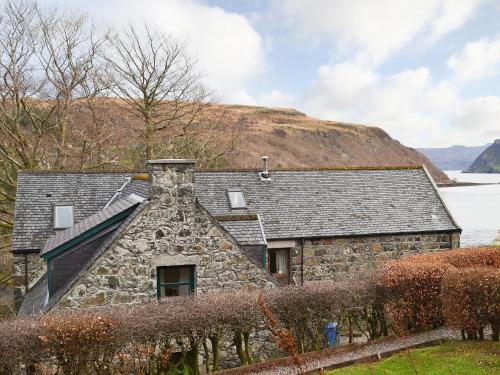 an old stone house with a hill in the background at Cornucopia in Portree