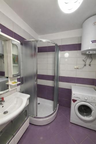 a bathroom with a shower and a sink and a washing machine at Aldi APARTMENTS in Lezhë