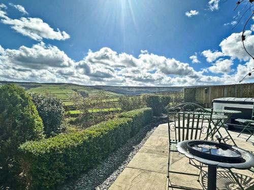 a patio with a table and chairs and the sun at Shelduck Cottage in Holmfirth