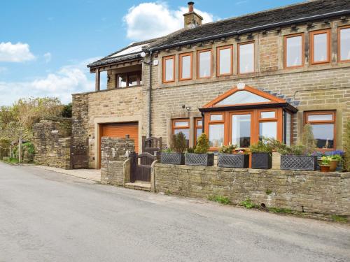 a brick house with a fence in front of it at Shelduck Cottage in Holmfirth