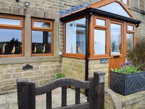 a small house with windows and a wooden fence at Shelduck Cottage in Holmfirth