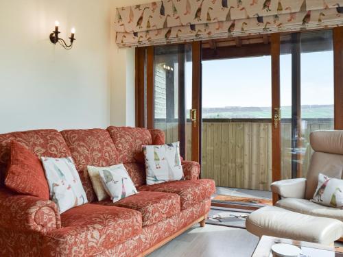 a living room with a red couch and a window at Shelduck Cottage in Holmfirth