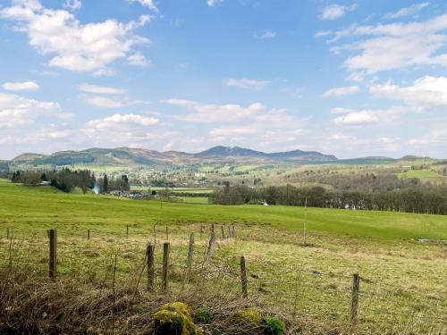 a field with a fence and mountains in the background at Whiteburn in Pitlochry
