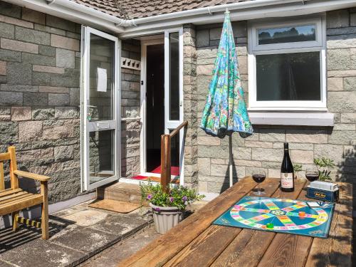 a patio table with a bottle of wine and an umbrella at Brynhafod in Llanfihangel-geneuʼr-glyn