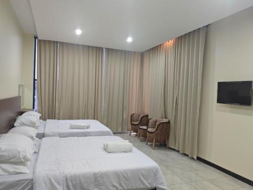 a hotel room with three beds and a flat screen tv at green hotel 2 ciamis in Ciamis