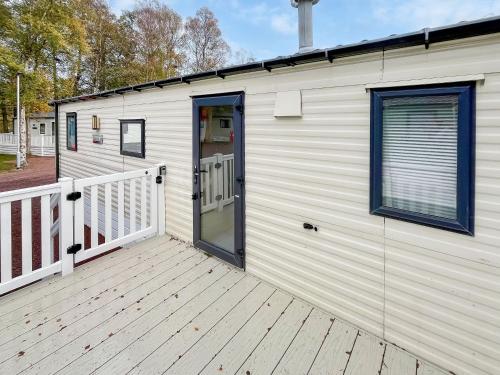 a small white building with a door and a porch at Eskside Lodge in Brechin