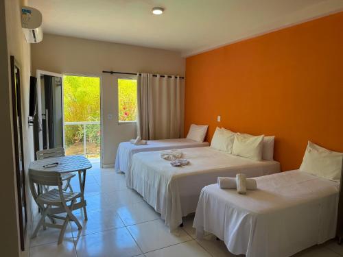 a bedroom with two beds and a table and a chair at Bela Vista Japaratinga Flats e Temporada in Japaratinga