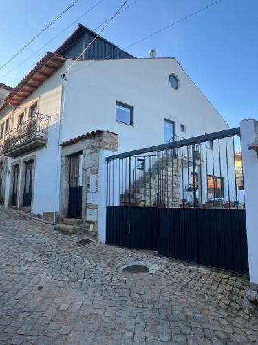 a white house with a black gate on a street at Casa das Romãs in Torre de Moncorvo