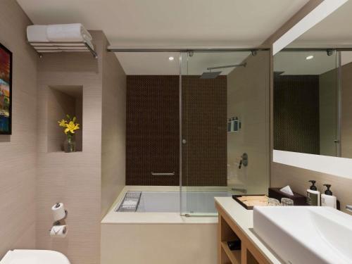 a bathroom with a shower and a toilet and a sink at Novotel Lucknow Gomti Nagar in Lucknow