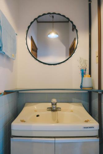 a bathroom with a sink and a mirror at ゲストハウス レトロマチカ in Sakai