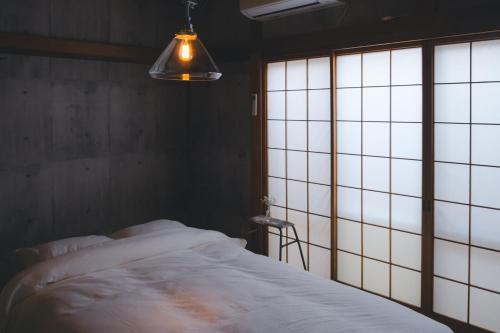 a bedroom with a bed and a large window at ゲストハウス レトロマチカ in Sakai