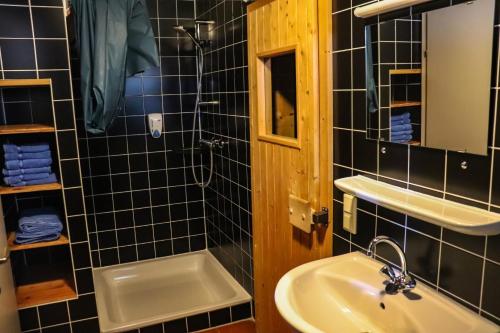 a black tiled bathroom with a sink and a shower at miki Chalets in Pack
