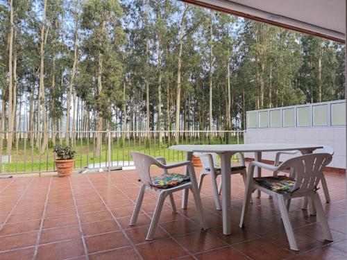 a table and chairs on a patio with trees at Nido Ría in Villaviciosa