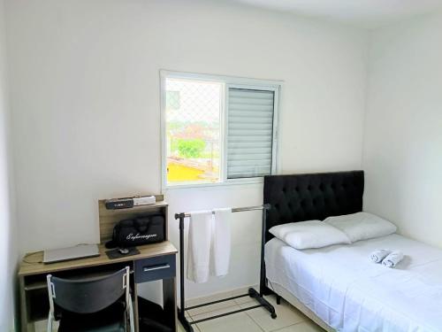 a bedroom with a bed and a desk with a computer at Condomínio - Dell Mar III in Bertioga