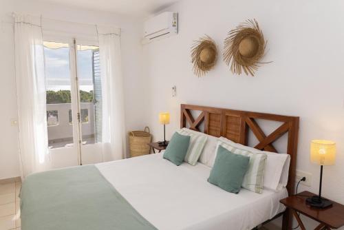 a bedroom with a large white bed and a window at Baconer - Casa en l'Ampolla con jardín privado y acceso directo al mar - Deltavacaciones in L'Ampolla