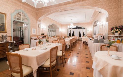 une salle à manger avec des tables et des nappes blanches dans l'établissement Hotel Du Parc, à Stresa