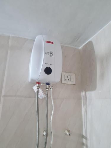 a white shower head on a wall in a bathroom at Umashankar Homestay in Nashik