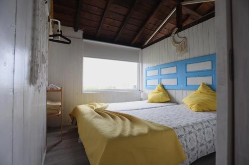 a bedroom with a bed with a blue headboard and yellow pillows at Casa dos Flamingos in Murtosa