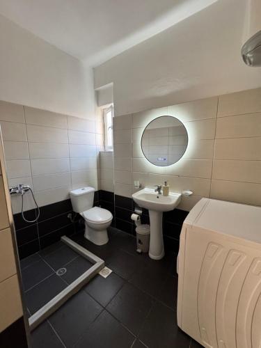 a bathroom with a sink and a toilet and a mirror at Eki Apartments in Sarandë