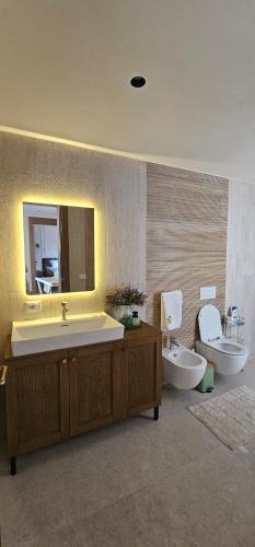 a bathroom with a sink and a toilet and a mirror at Huma Living in Vlorë
