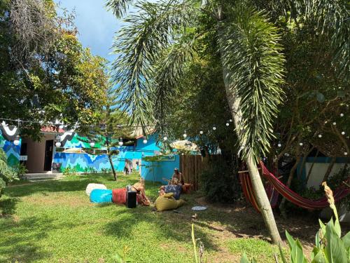 Eine Gruppe von Menschen sitzt im Gras unter einer Palme in der Unterkunft Kohmunity Hostel in Thongsala