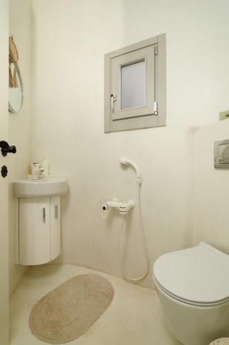 a white bathroom with a toilet and a sink at West Side Garden House in Gavrio