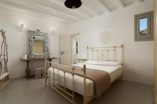 a white bedroom with a bed and a mirror at West Side Garden House in Gavrio