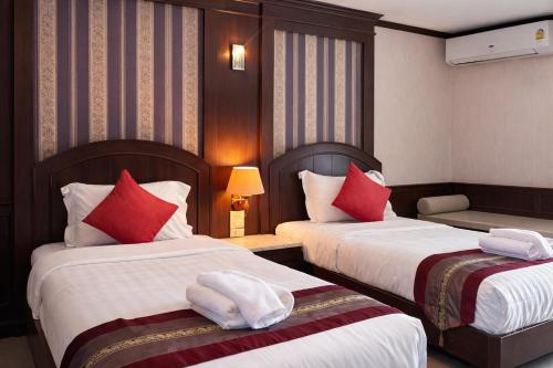 a hotel room with two beds with red pillows at The Lion King Hotel by Thai Baan Ozone Udonthani in Udon Thani