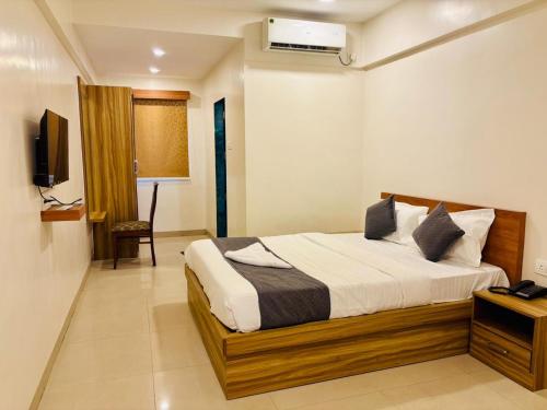a bedroom with a bed and a television in it at Hotel Aura Inn in Dehu