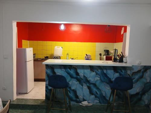 a kitchen with a counter and two blue stools at Les Jasmins partagées in Mamoudzou